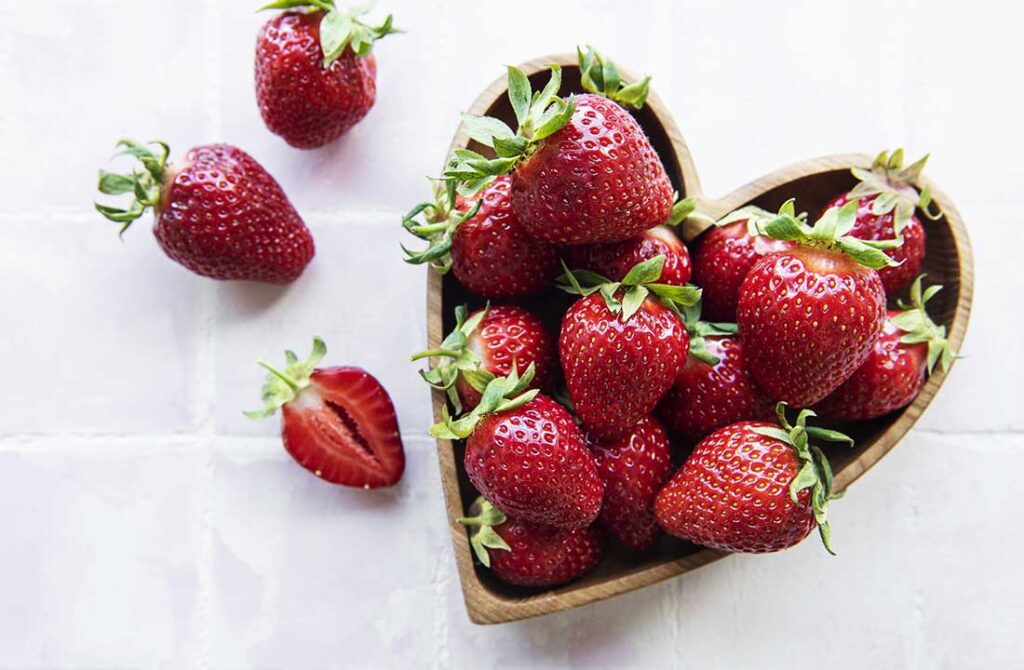 frische gepflückte erdbeeren in einer schale mit herzform