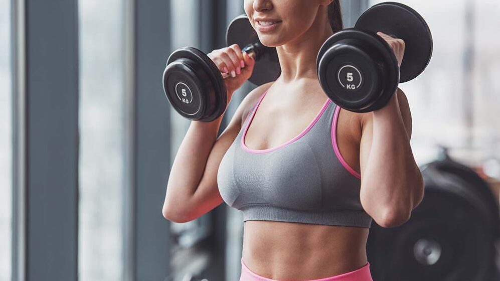 frau beim schulter krafttraining mit kurzhanteln